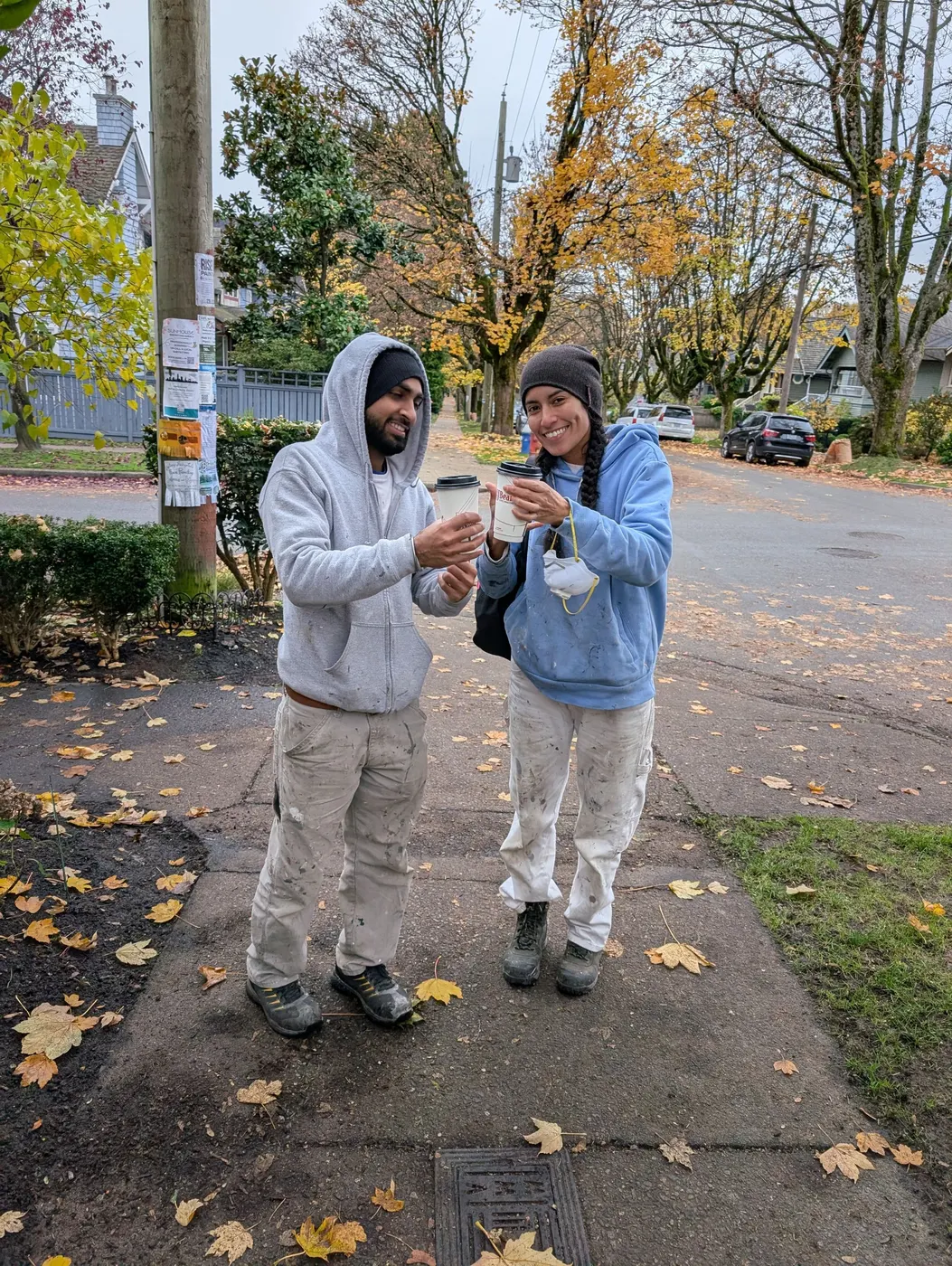 Two Renaissance Painting crew members sharing a coffee break on a Vancouver street during a job.