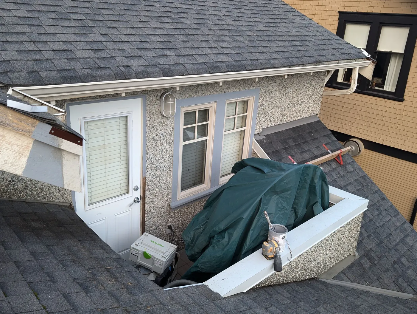 Dormer window and roof section of a Vancouver home covered with a tarp during exterior painting prep.