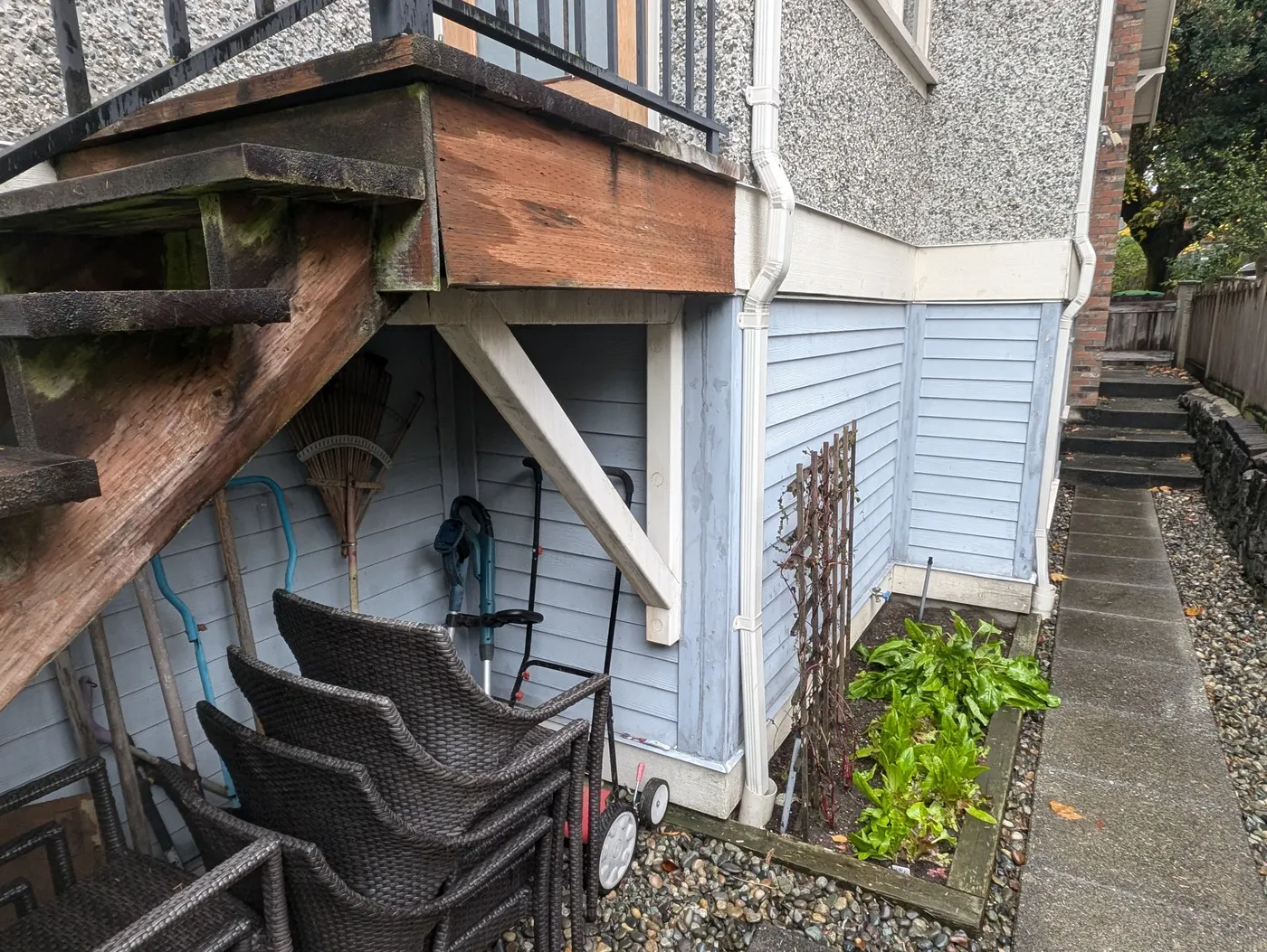 Weathered blue-grey wood siding and deck framing on a Vancouver home prior to exterior painting.