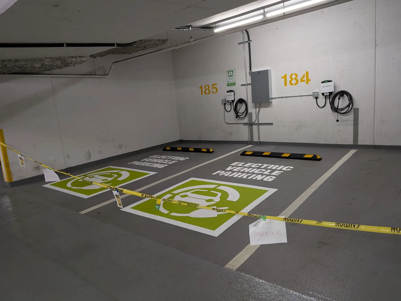 Two completed EV parking stalls with green charging symbols and Electric Vehicle Parking text in a Vancouver condo parkade.