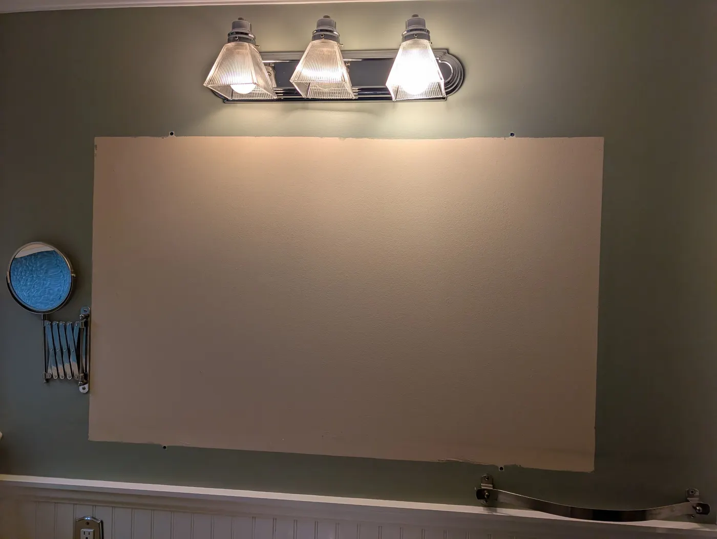 Bathroom wall prepped with a patched and primed drywall section beneath a chrome vanity light fixture, part of an interior painting project in Vancouver, BC.