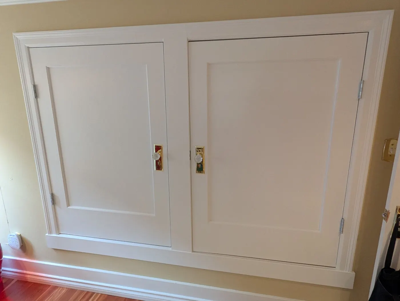 Two painted white built-in cabinet doors with brass hardware and crystal knobs, finished by Renaissance Painting in a Vancouver, BC home.