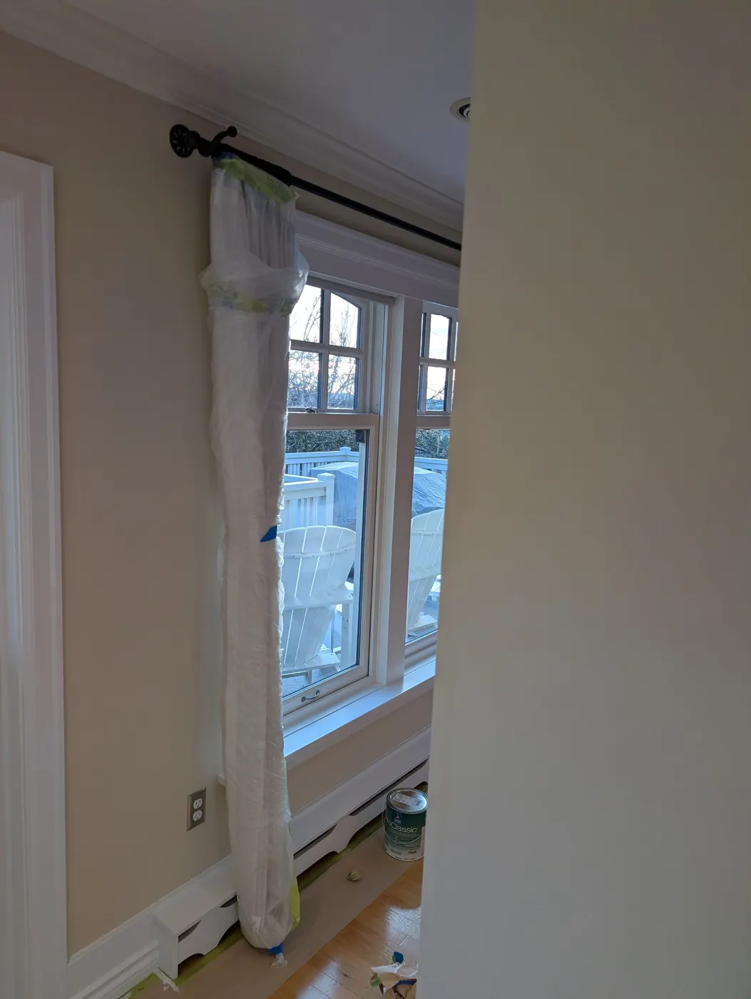 Masked curtain and window trim with crown moulding and a paint can during interior painting prep in a Vancouver, BC home.