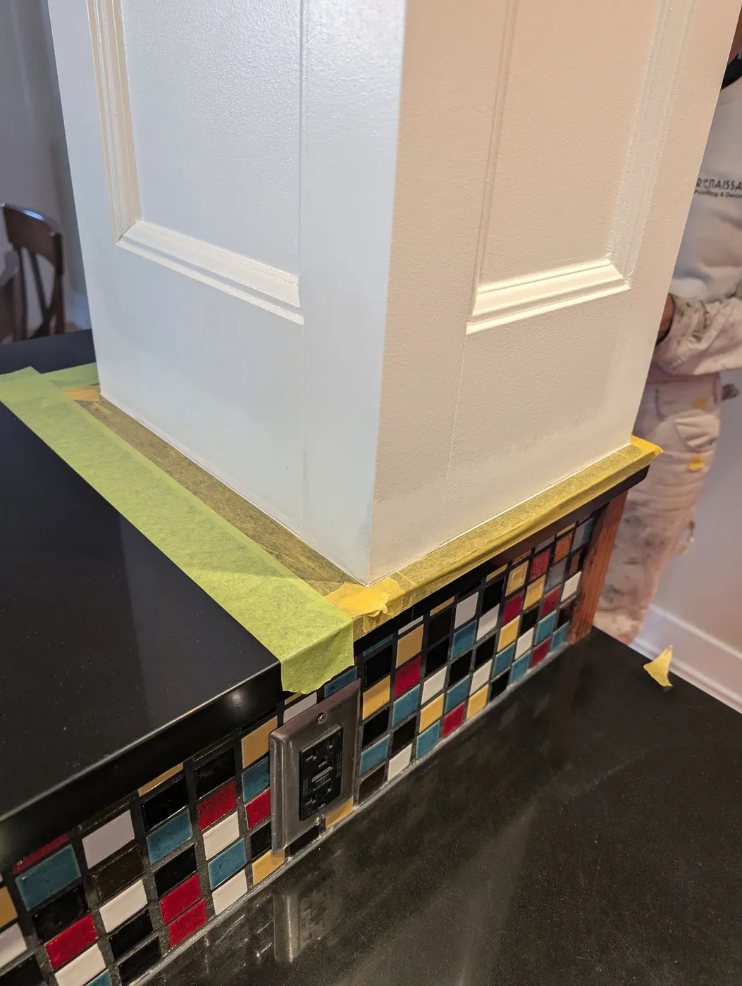 Renaissance Painting crew member finishing a white kitchen island column beside colorful mosaic tile in a Vancouver, BC home.