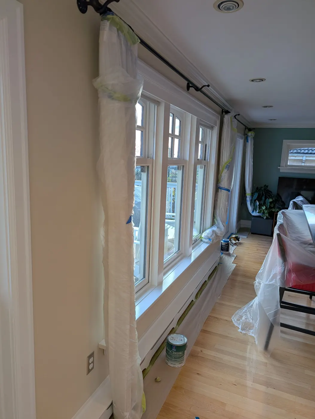 Living room window and trim masked with plastic sheeting during an interior painting project by Renaissance Painting in Vancouver, BC.