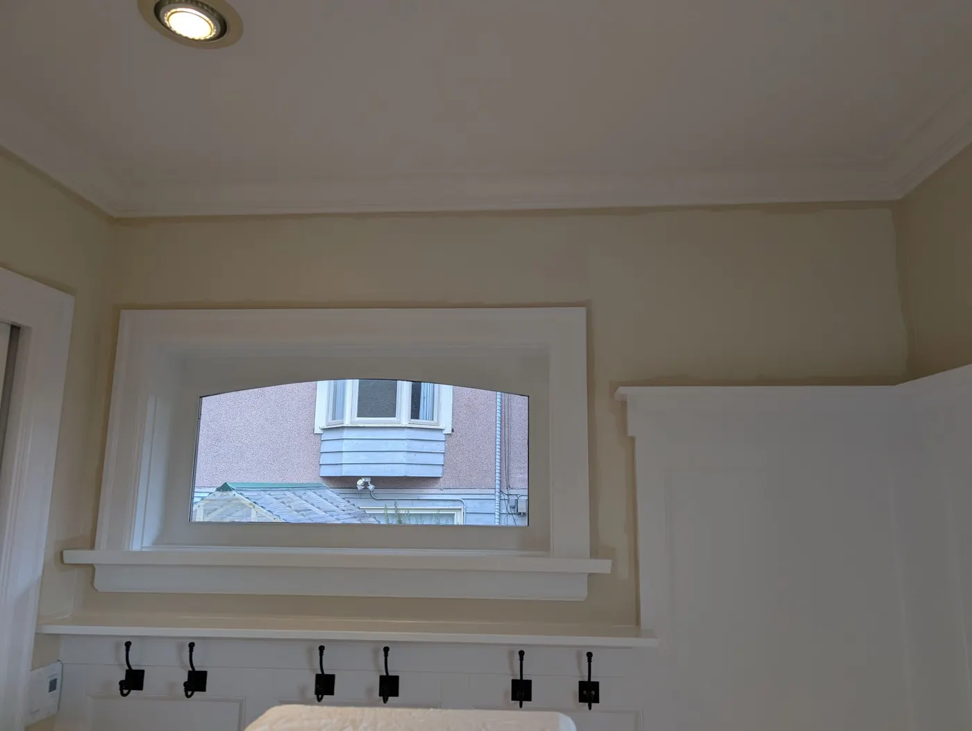 Crisp white-painted window trim and built-in coat hooks in a Vancouver, BC mudroom, finished by Renaissance Painting.