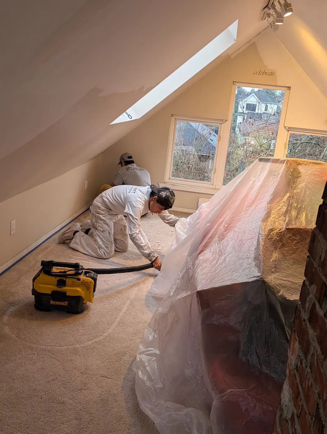 Renaissance Painting & Carpentry crew setting up plastic dust barriers and vacuuming before painting an attic bedroom in Vancouver, BC