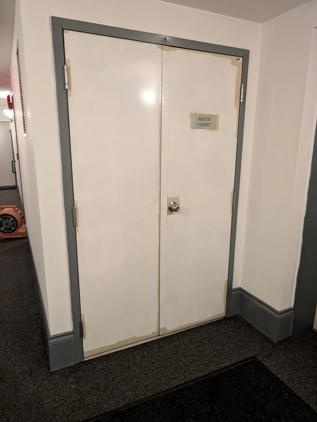 Freshly primed and taped Meter Closet double door in a Vancouver condo hallway, prepped for a clean interior repaint.
