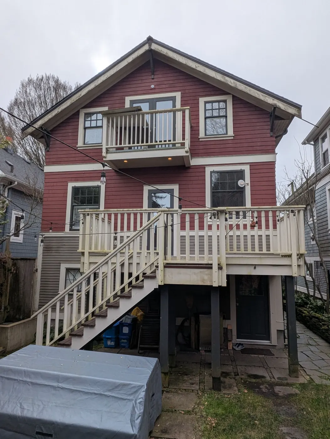 Rear elevation of a Vancouver, BC red craftsman home with weathered deck and siding before an exterior painting project.