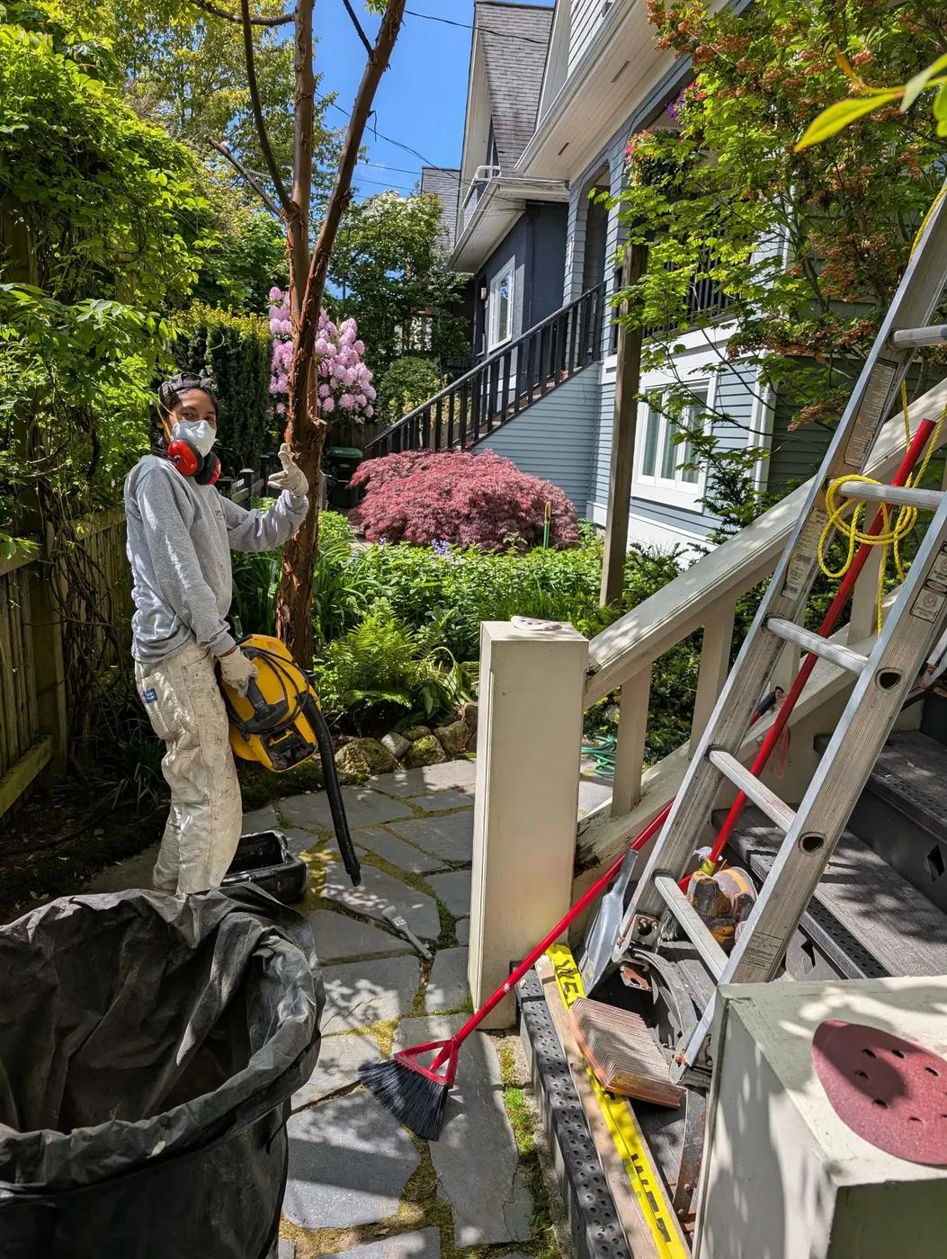 Renaissance Painting crew member wearing a respirator and safety gear with a dust extractor vacuum on a residential job site in Vancouver, BC.