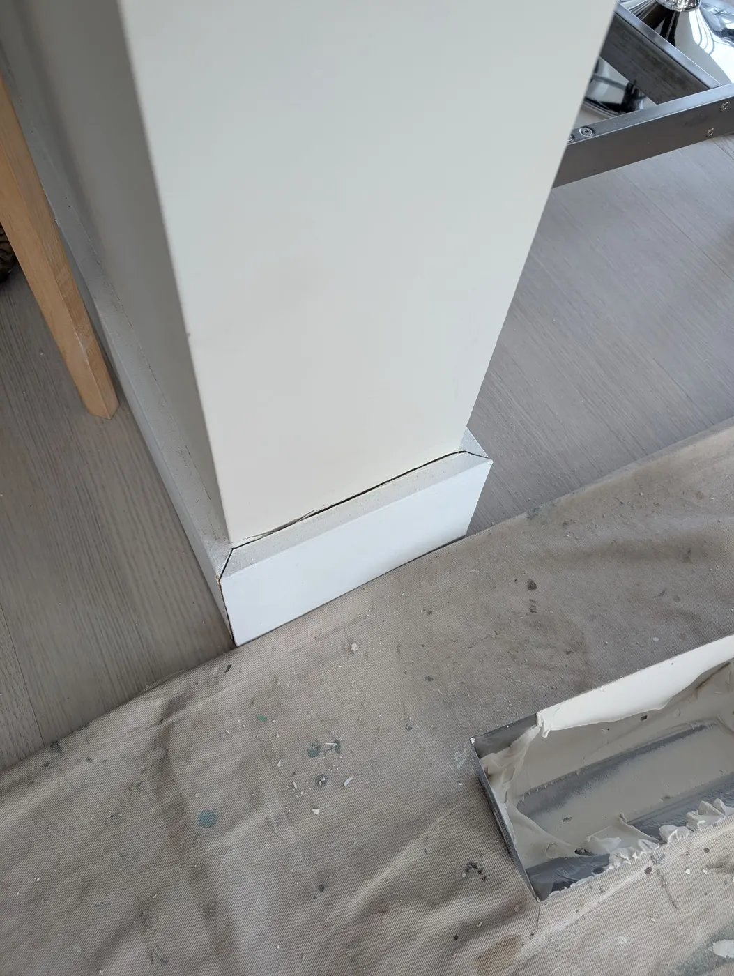 Close-up of a baseboard corner seam being repaired and caulked in a Vancouver, BC condo interior.