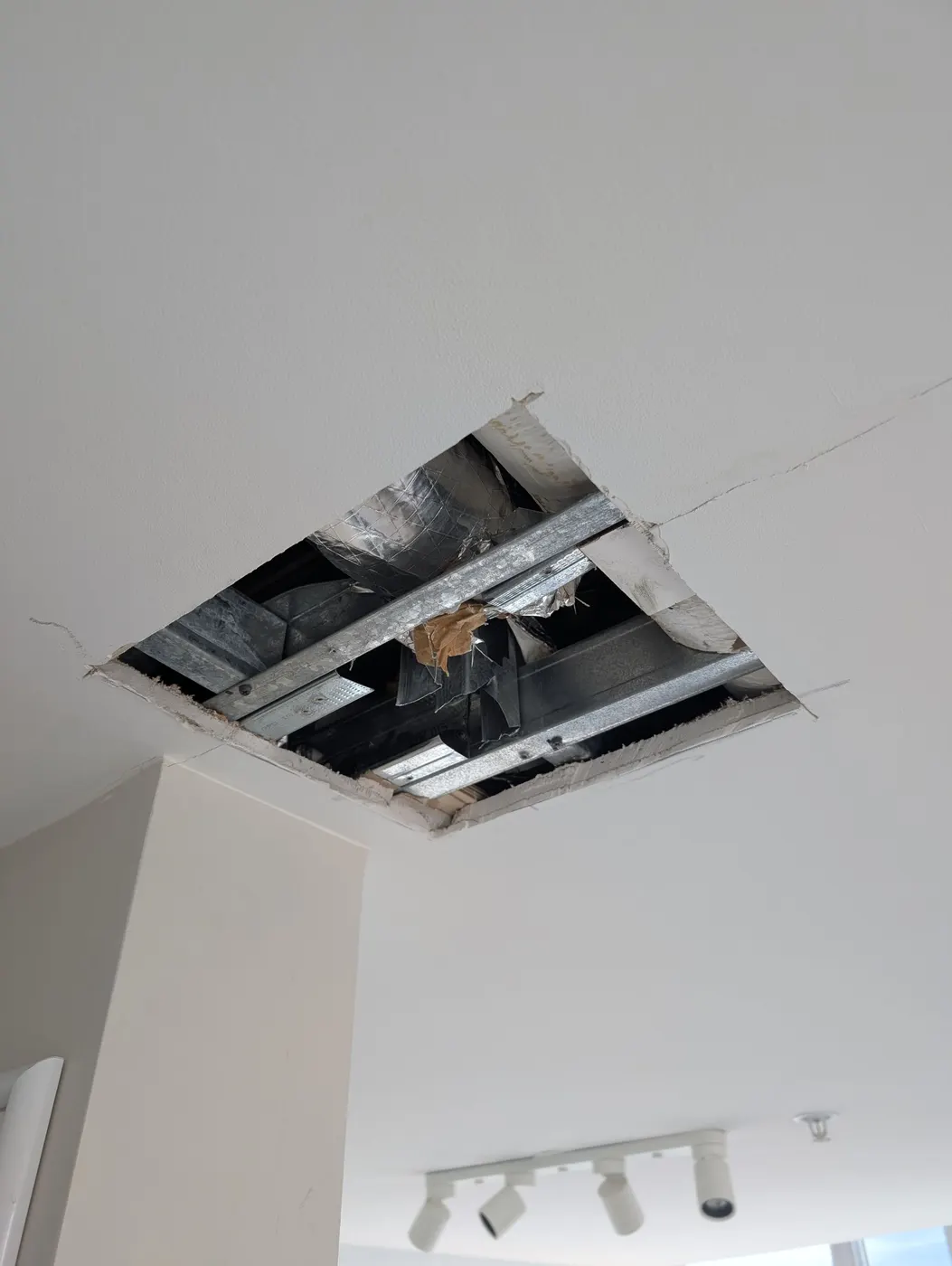Exposed ceiling drywall damage before repair in a Vancouver, BC condo, showing joists and ductwork ahead of Renaissance Painting's drywall patch work.