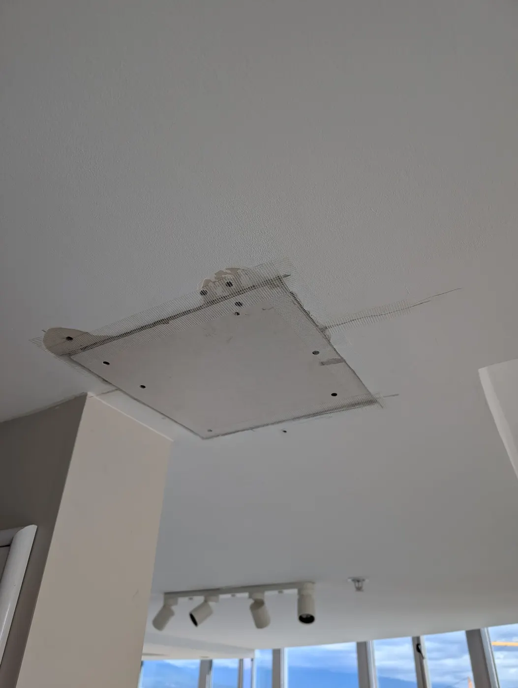 Mesh joint tape applied over a ceiling drywall patch seam during interior repair in Vancouver, BC.