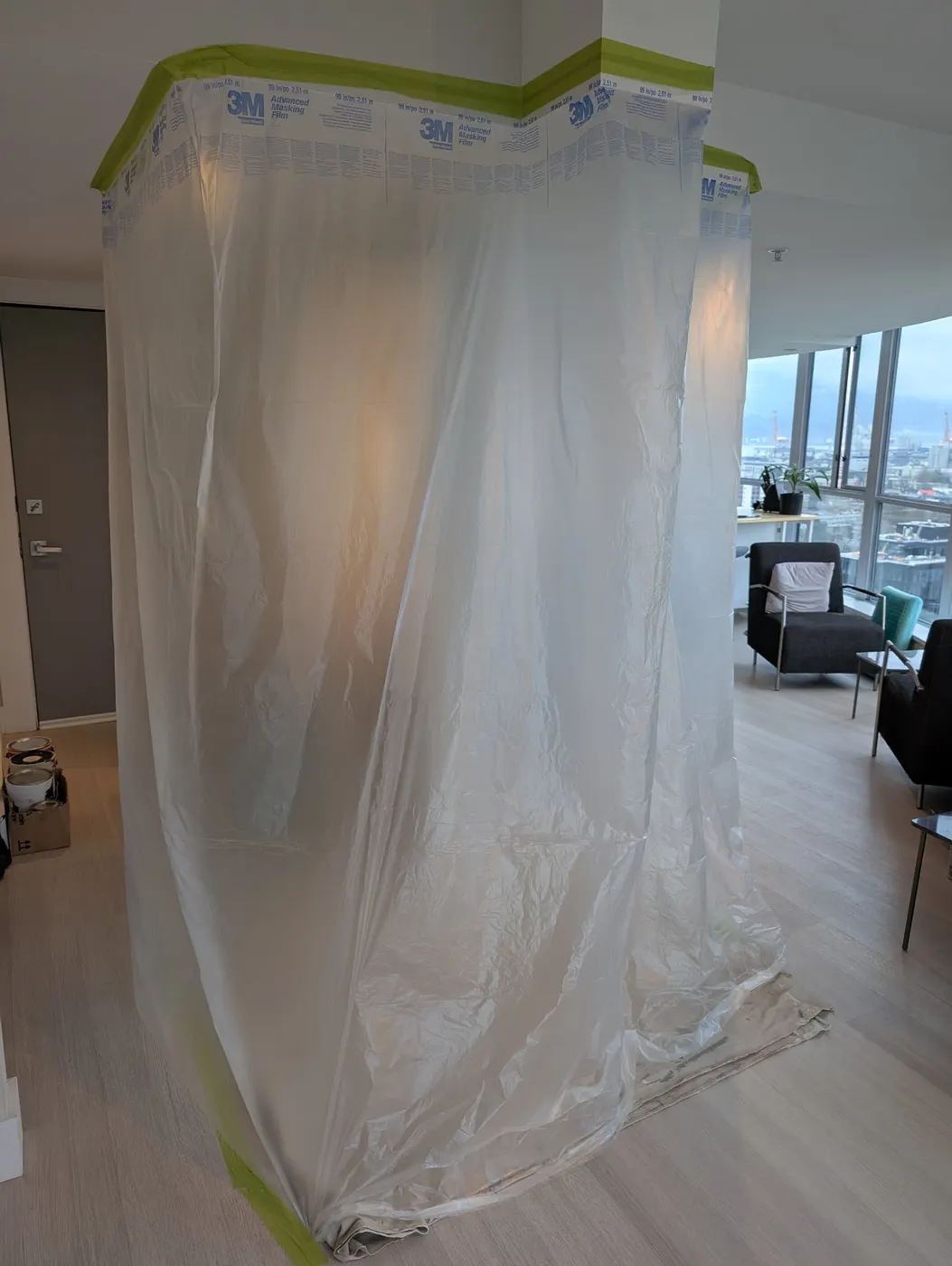 Plastic sheeting and masking film protecting a room corner during interior painting prep in a Vancouver, BC condo.