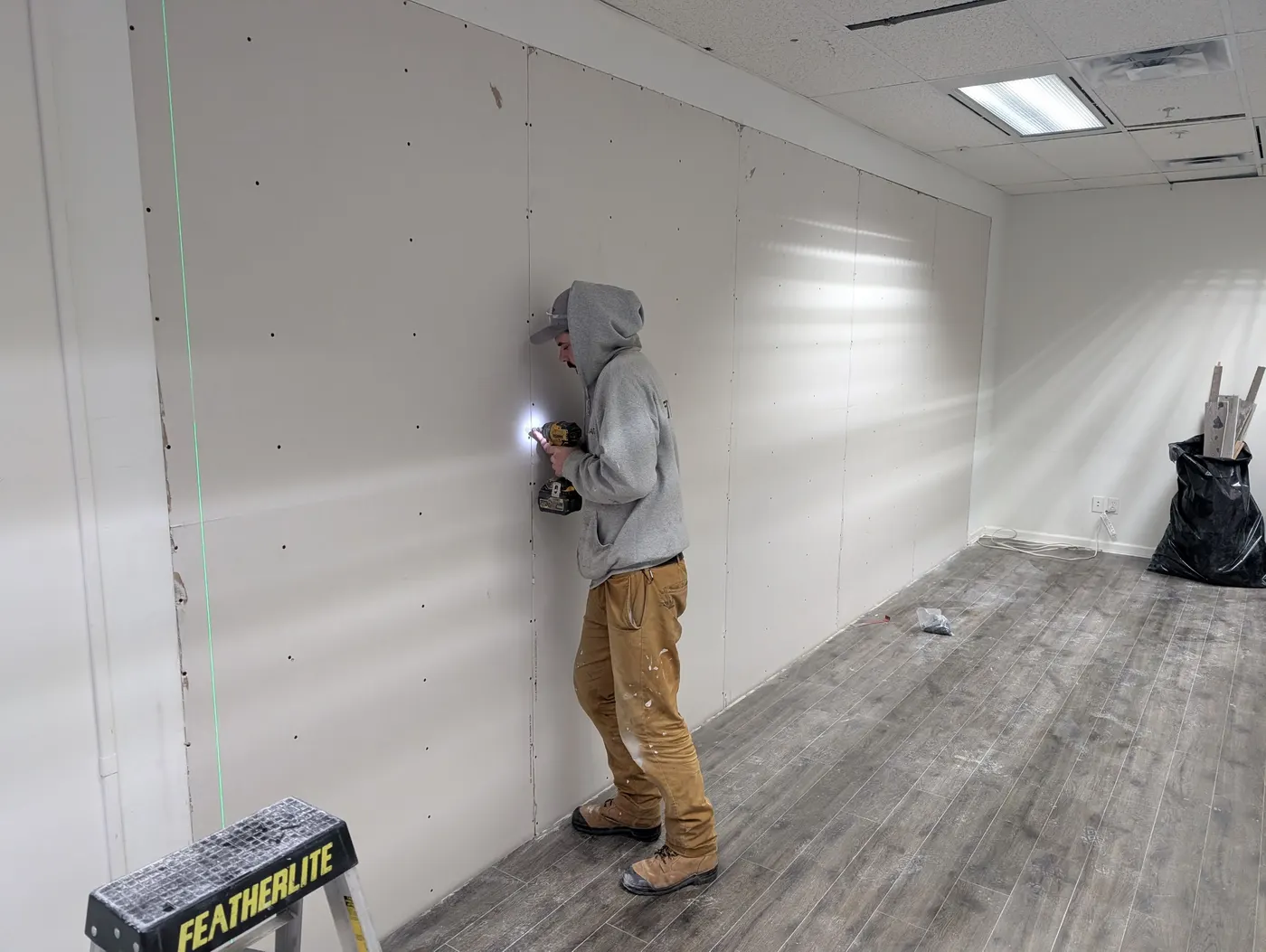 Painter applying drywall patches before painting an interior office wall in Vancouver, BC
