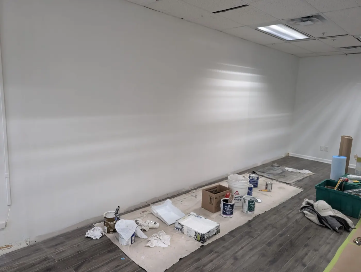 Finished white interior wall with paint cans and rollers in a Vancouver commercial painting project