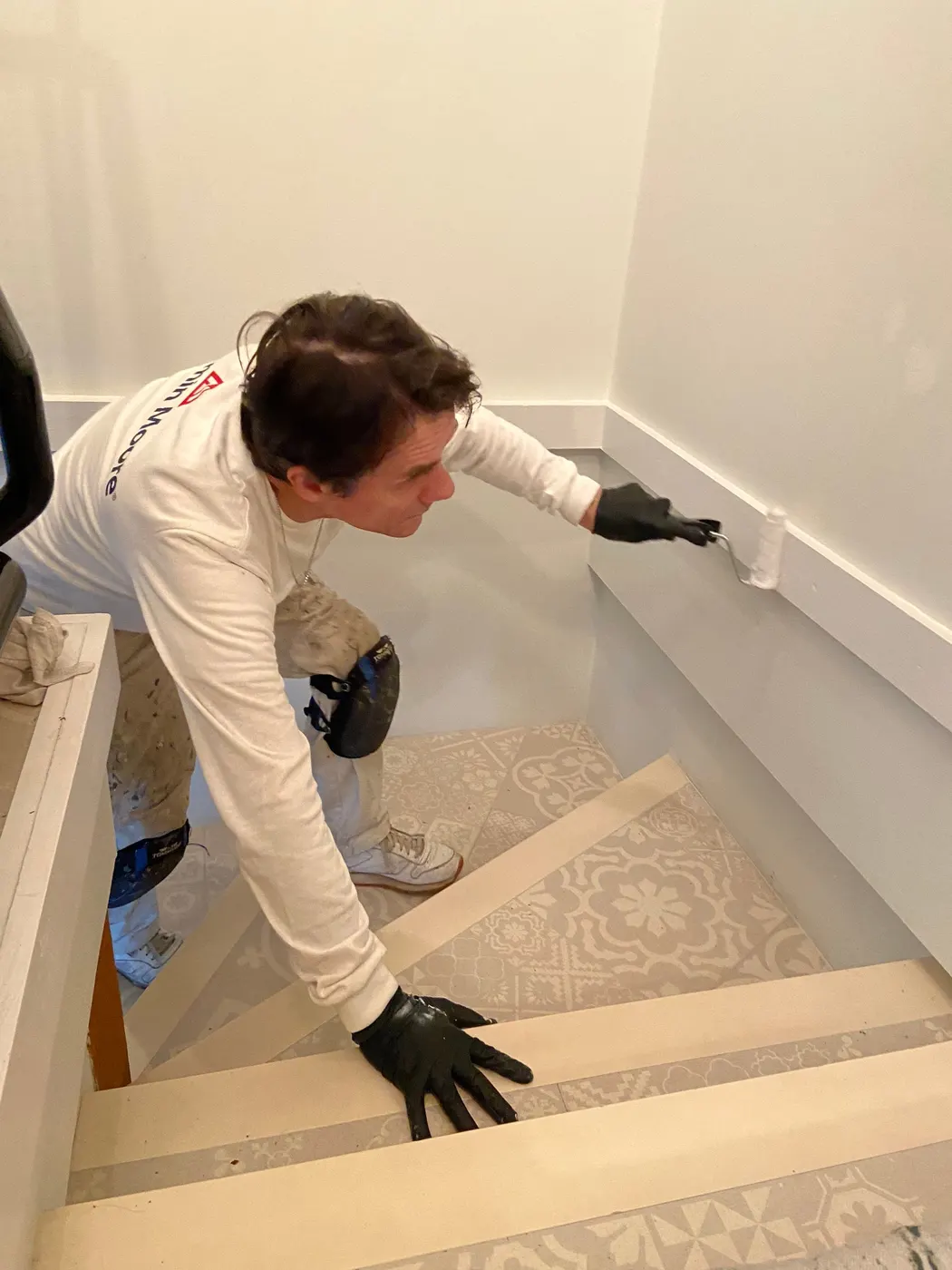 Painter taping a vaulted ceiling corner before repainting a Vancouver living room.