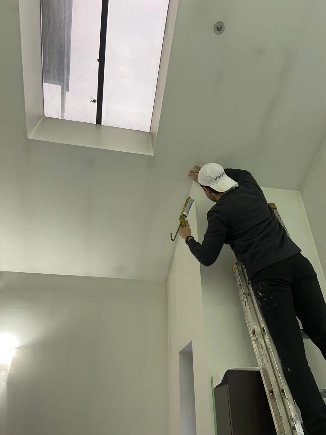 Painter on a step stool painting door trim in a protected Vancouver kitchen.