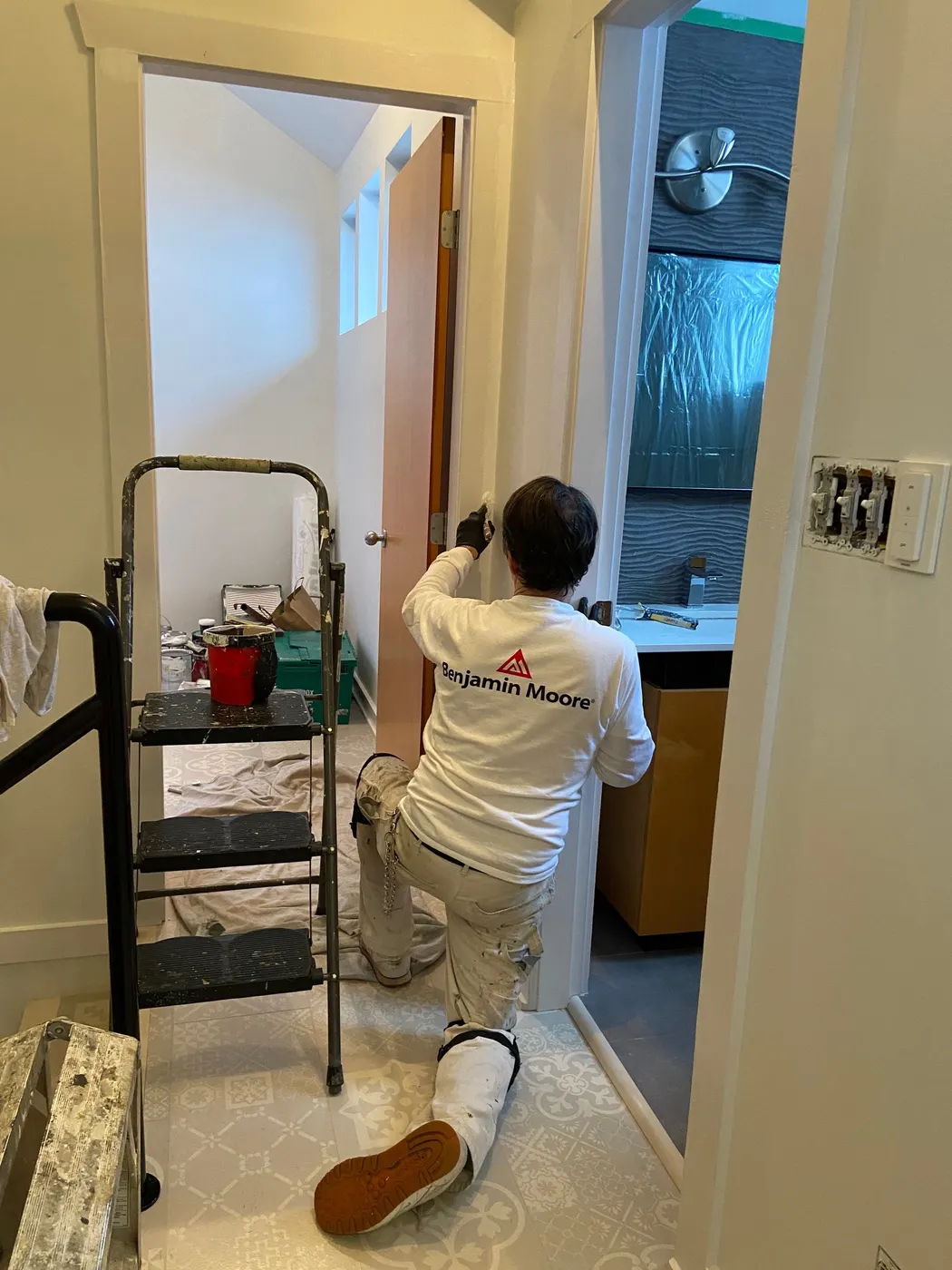 Painter rolling wall paint on a stairwell landing in a Vancouver home renovation.