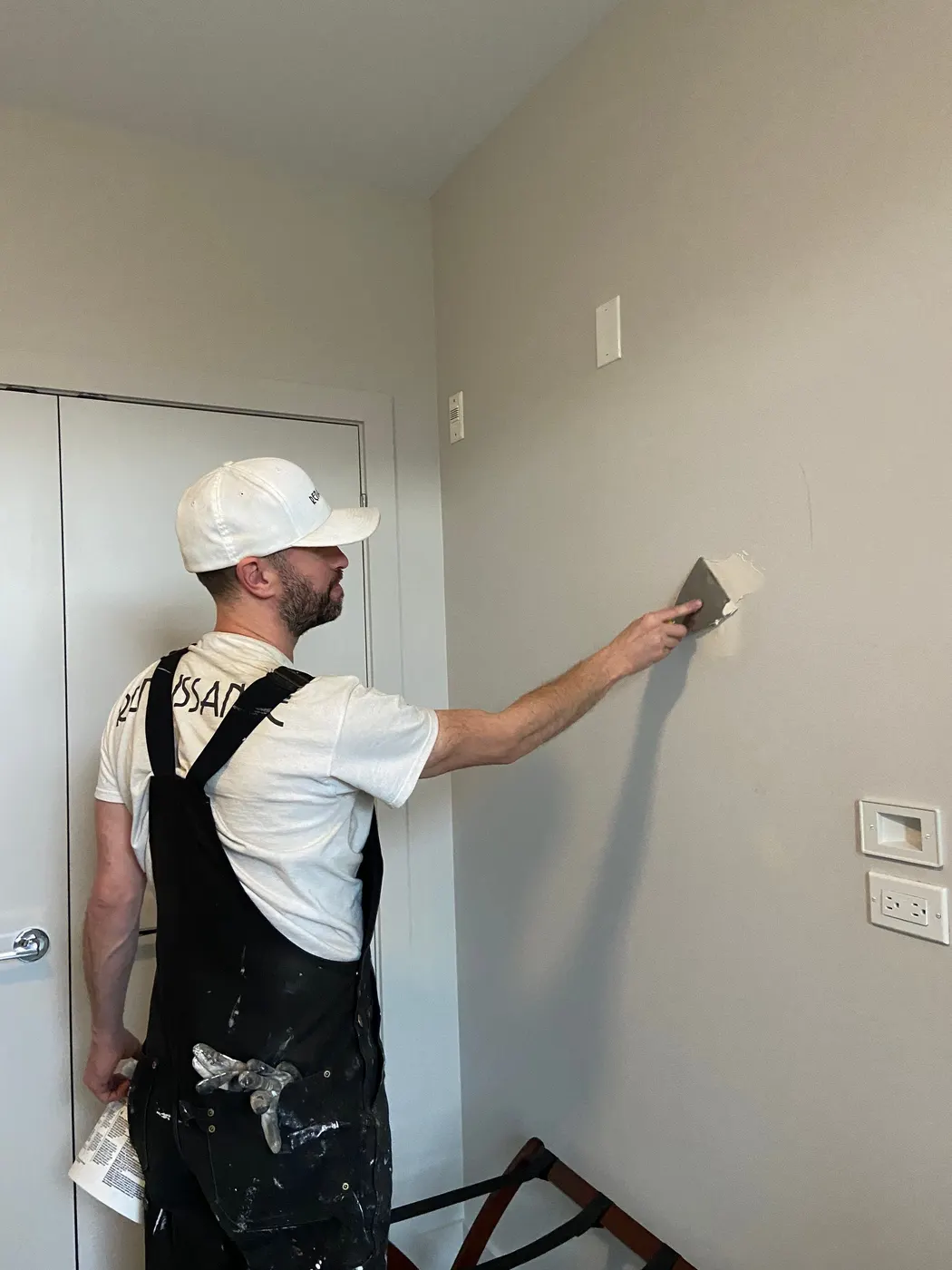 A Renaissance Painting drywall finisher smooths a patched wall corner before priming in a Vancouver, BC home renovation.