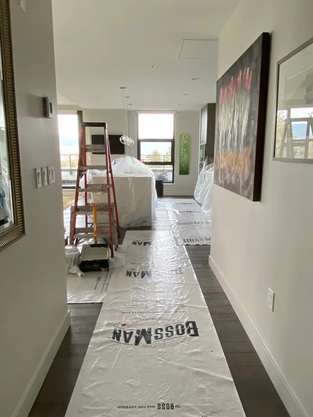 A ladder and protective floor coverings set up in a Vancouver, BC condo hallway during an interior painting project.