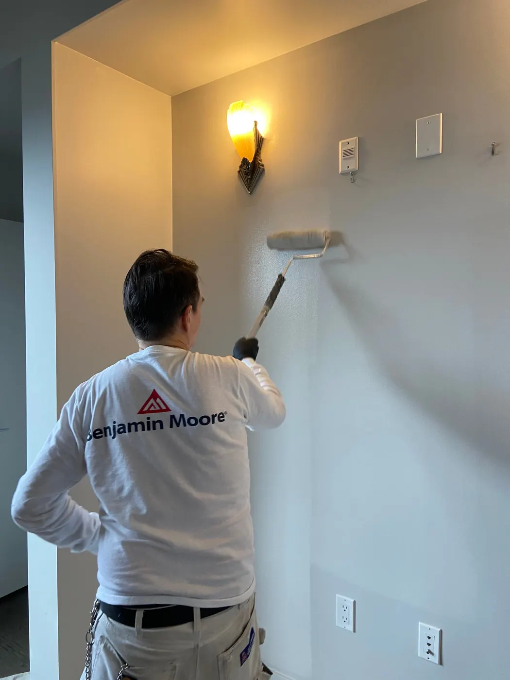 A painter rolls Benjamin Moore paint onto an interior wall during a Vancouver, BC condo repaint.