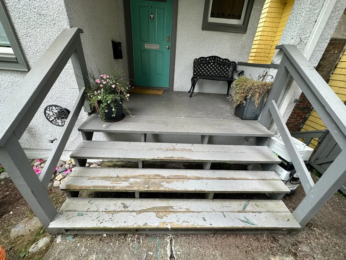 Peeling grey paint on wooden front porch steps before repainting in Vancouver, BC