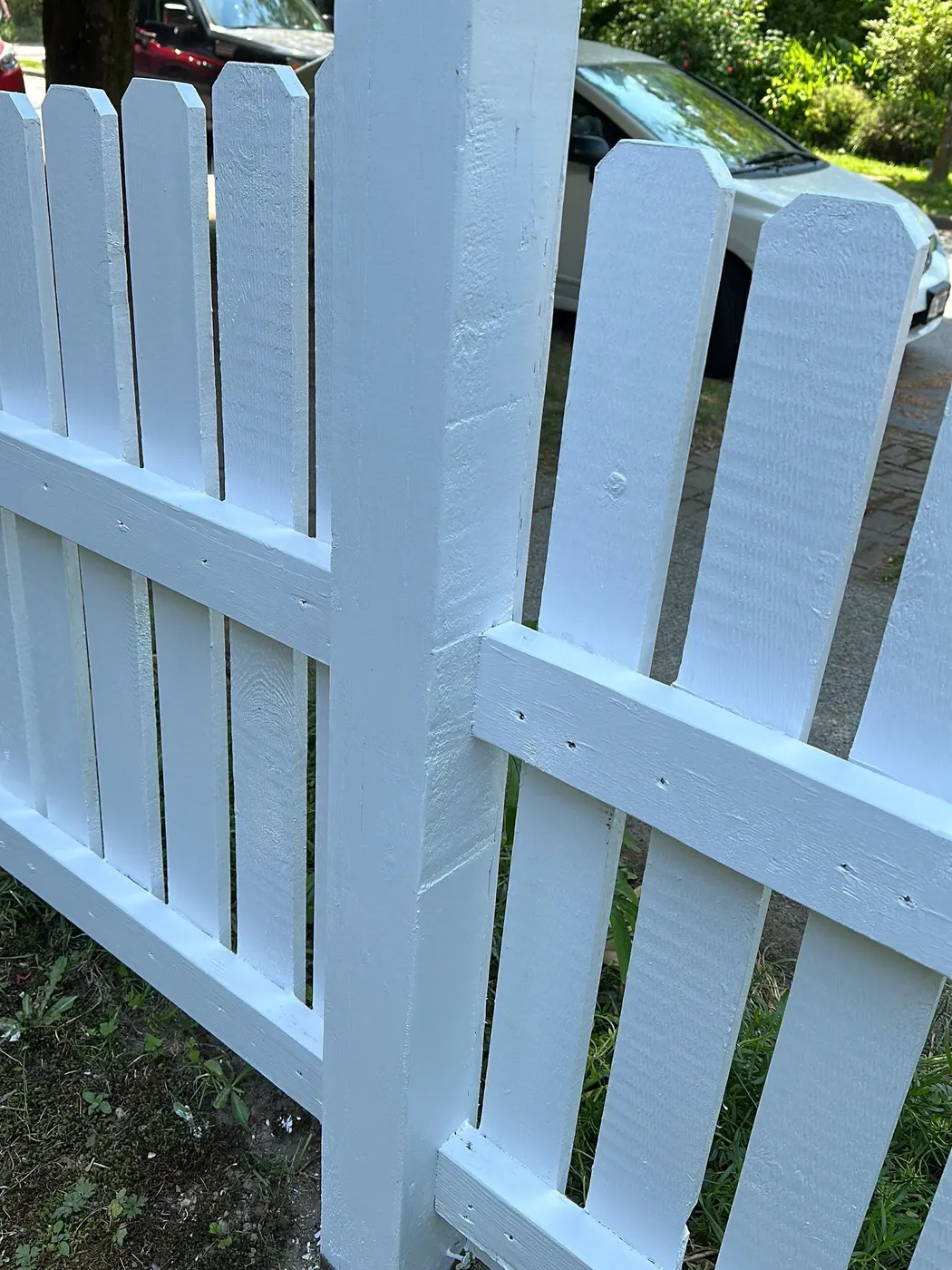Freshly painted white picket fence corner post in a Vancouver, BC front yard