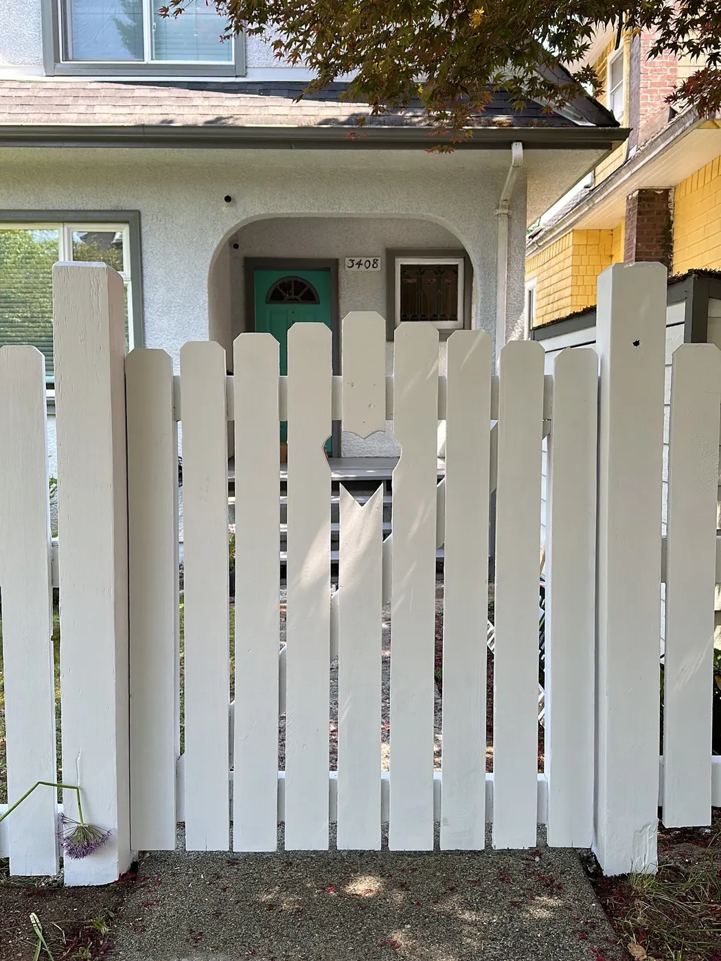 Freshly repainted white picket fence gate with heart cutout in Vancouver, BC
