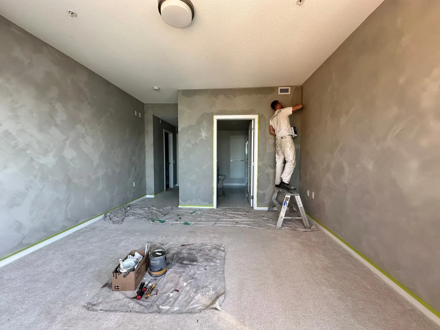 Renaissance Painting crew member on a ladder finishing a Venetian plaster wall near the ceiling in a Vancouver, BC condo.