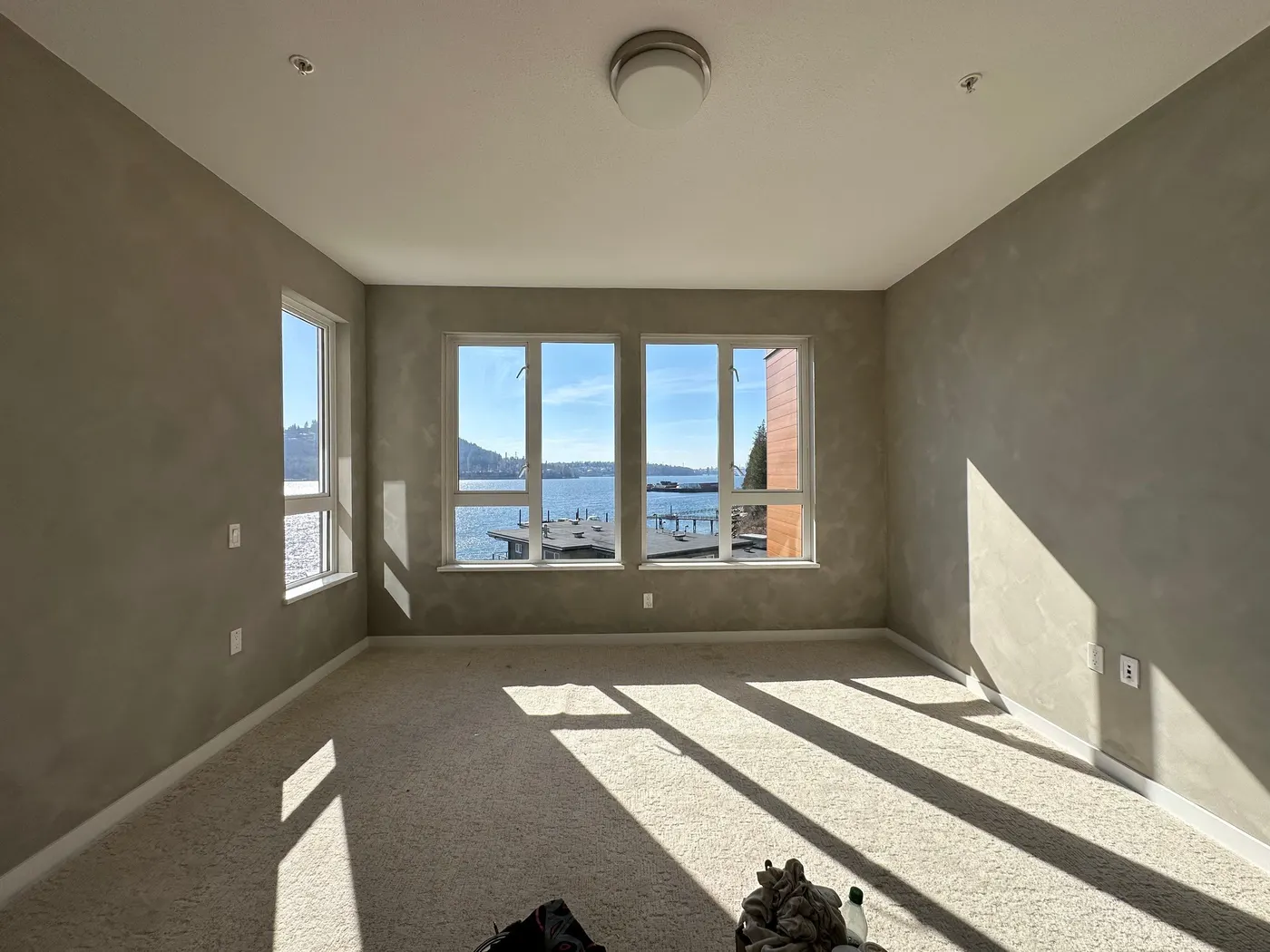 Sunlit bedroom with grey Venetian plaster walls and ocean views in a completed Vancouver, BC condo interior.