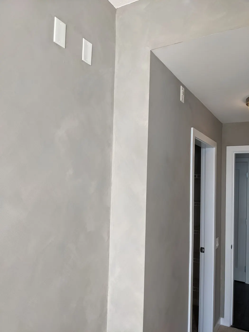 Smooth grey Venetian plaster walls and crisp white trim at a hallway corner in a completed Vancouver, BC condo.