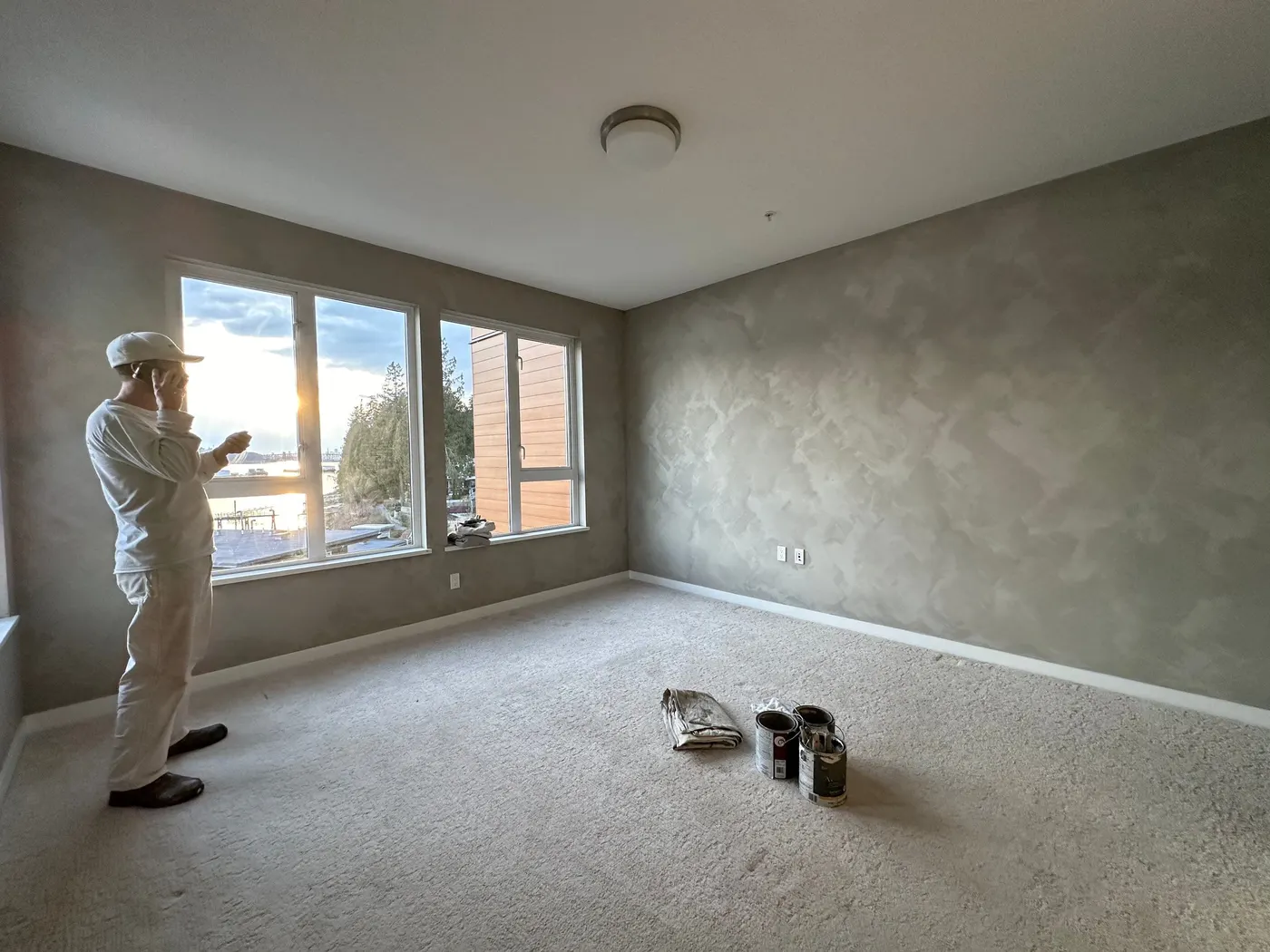 Painter reviewing the finished Venetian plaster accent wall in a Vancouver, BC condo bedroom with ocean views.