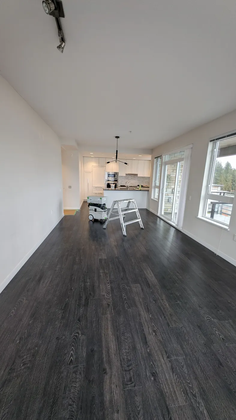 Protected hardwood floors and painting equipment set up in an open-concept Vancouver, BC condo kitchen and living area during an interior repaint.
