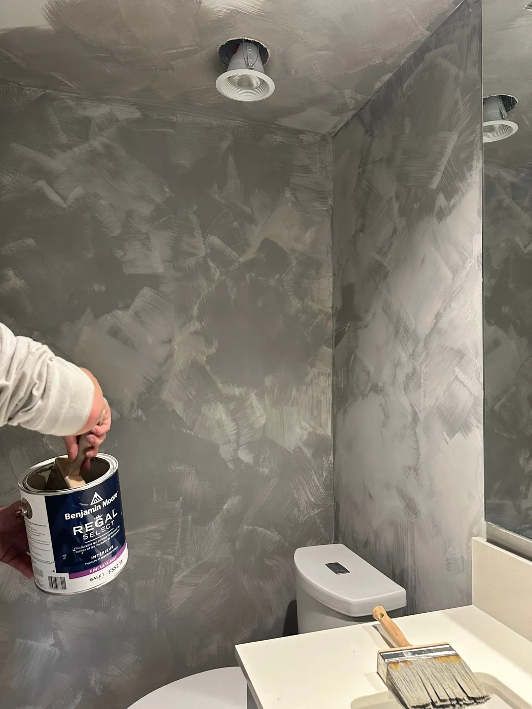 Painter applying a textured Venetian plaster finish to bathroom walls in a Vancouver, BC condo renovation.