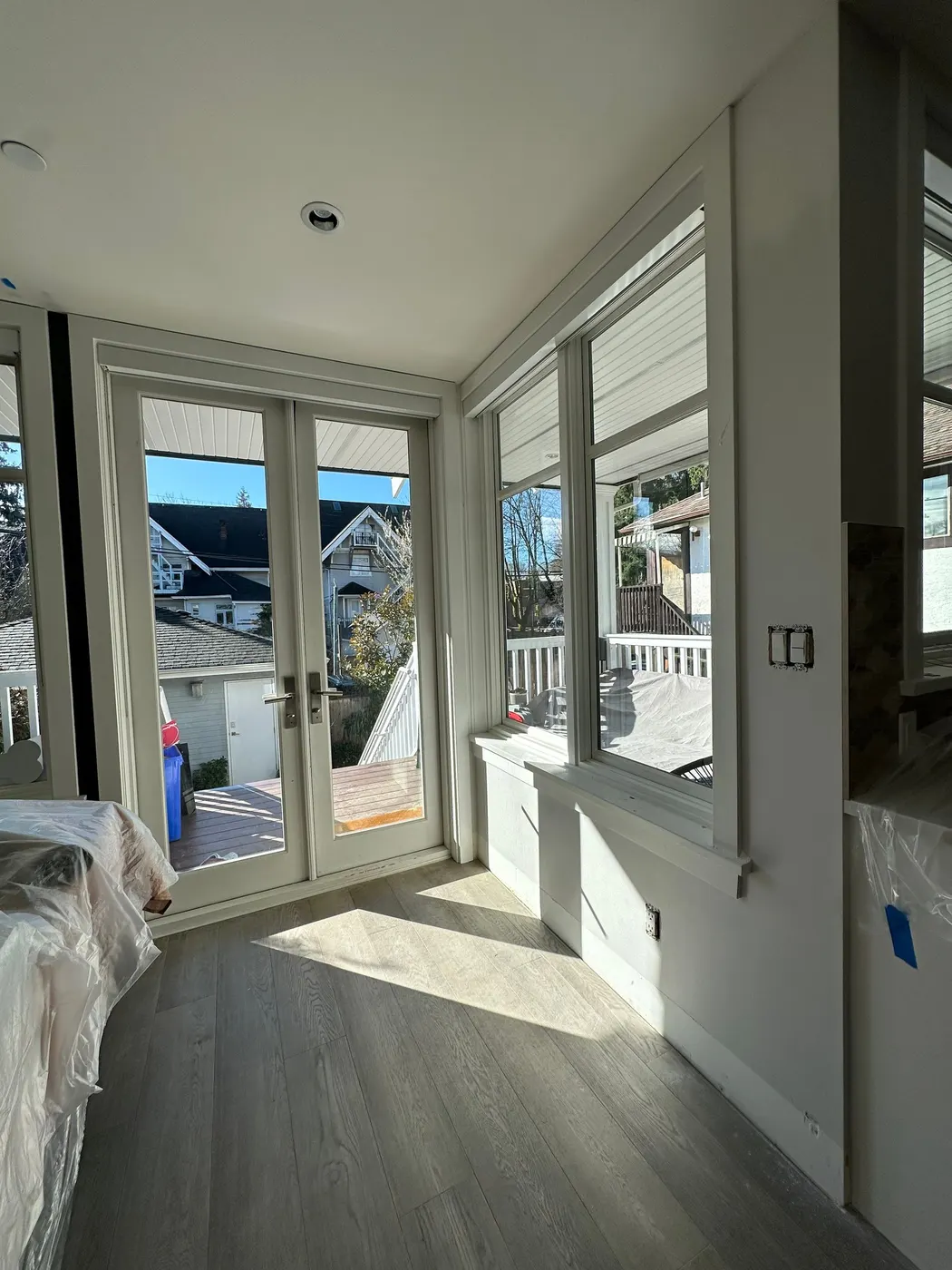 Freshly painted bright bedroom with French doors in a Vancouver, BC home renovation.
