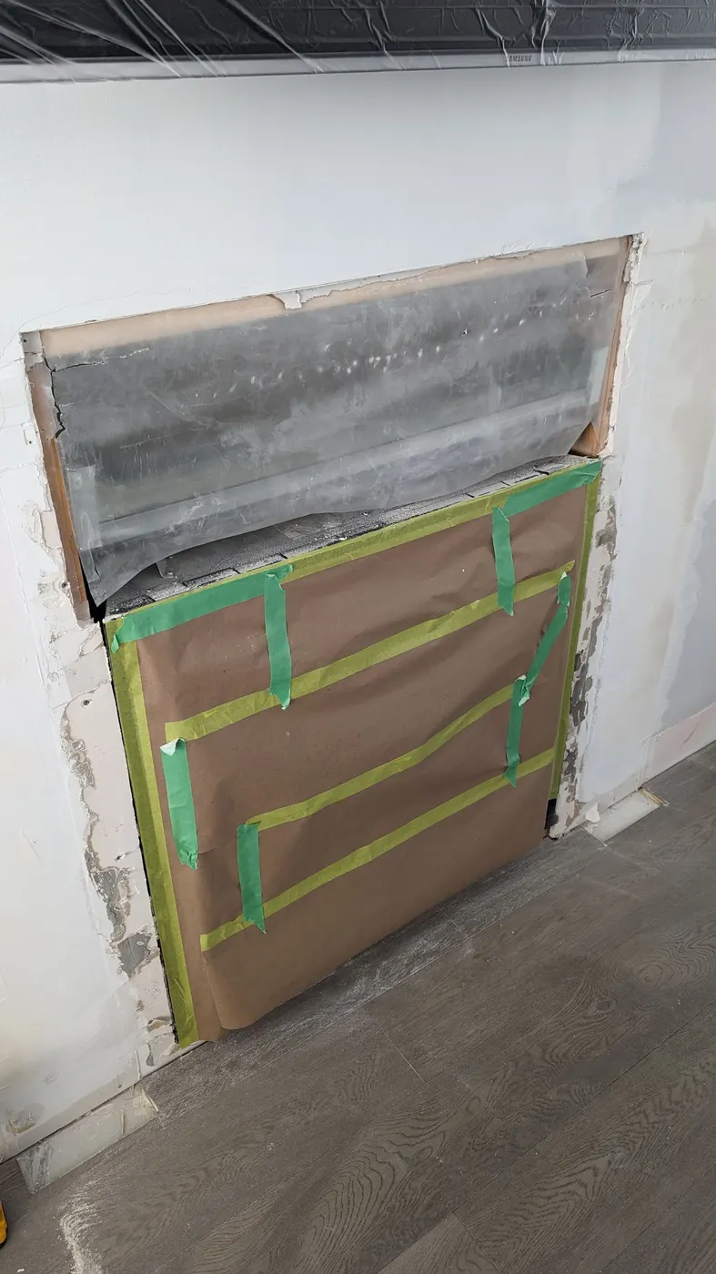 Drywall patch and protective covering above a fireplace insert during a Vancouver renovation.