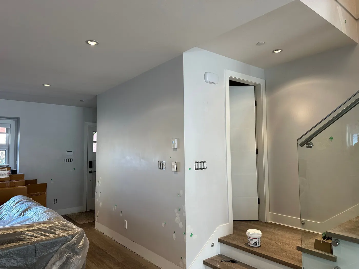 Patched drywall wall near a staircase in a Vancouver home ready for painting.