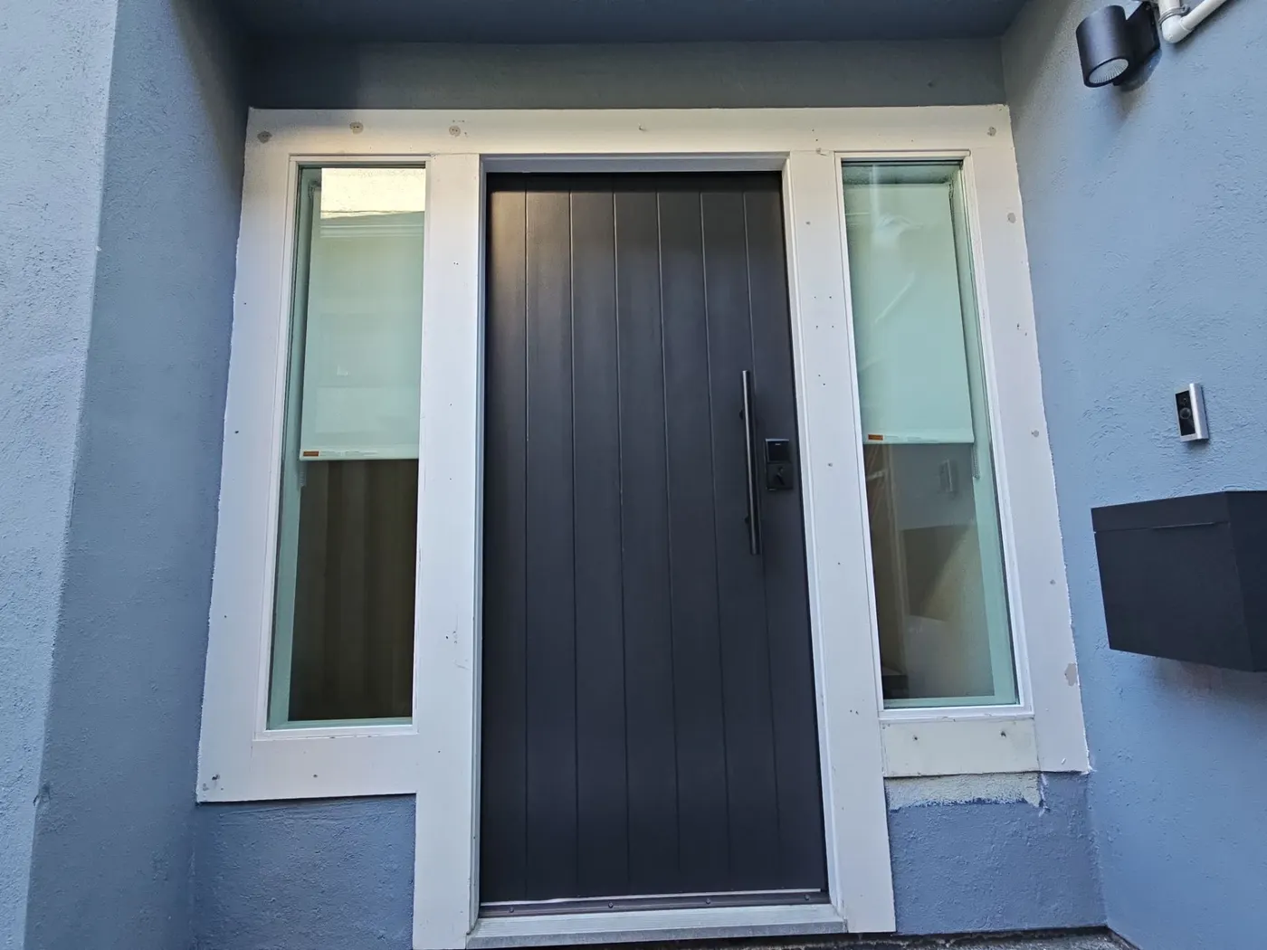 Modern dark grey front door with sidelight windows freshly finished on a Vancouver, BC home
