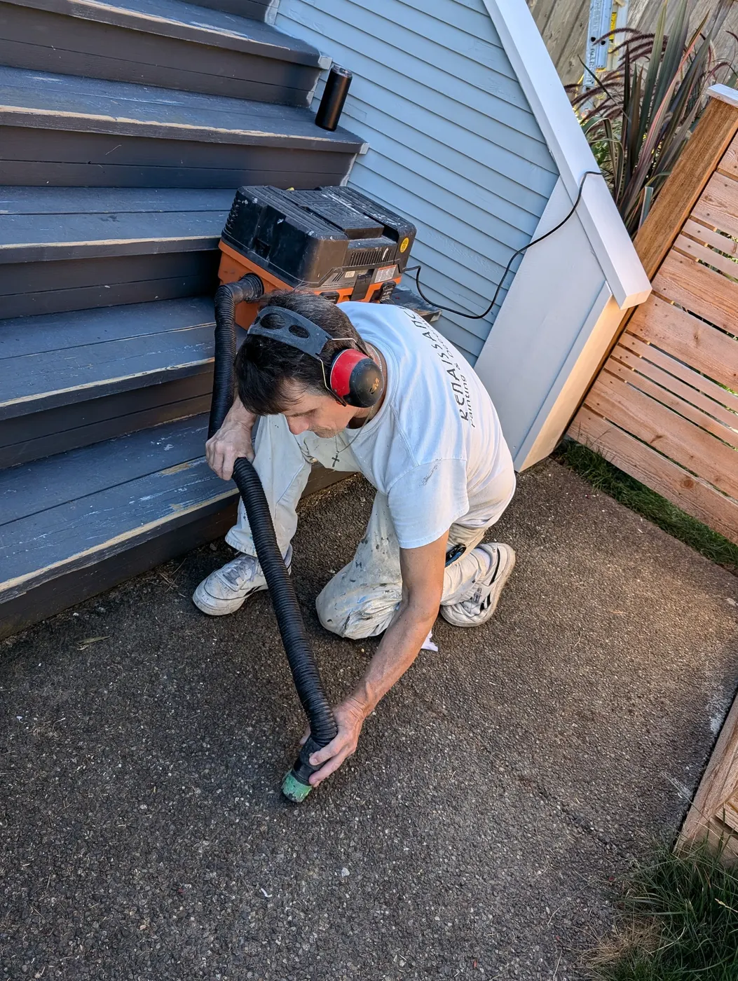 Renaissance Painting crew member in Vancouver, BC using a vacuum sander to prep wood steps before repainting