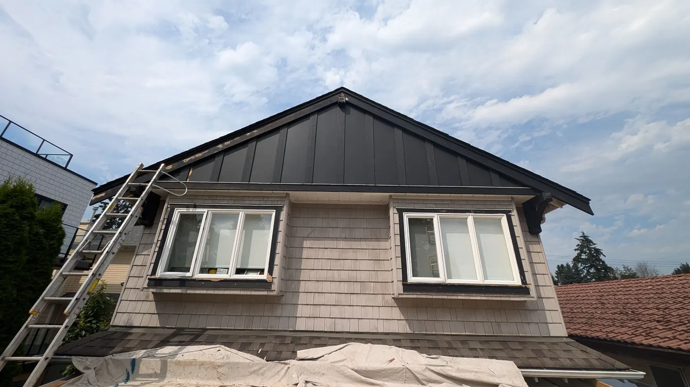 Craftsman-style Vancouver, BC home with dark gable roofline and dormer windows during exterior carpentry work