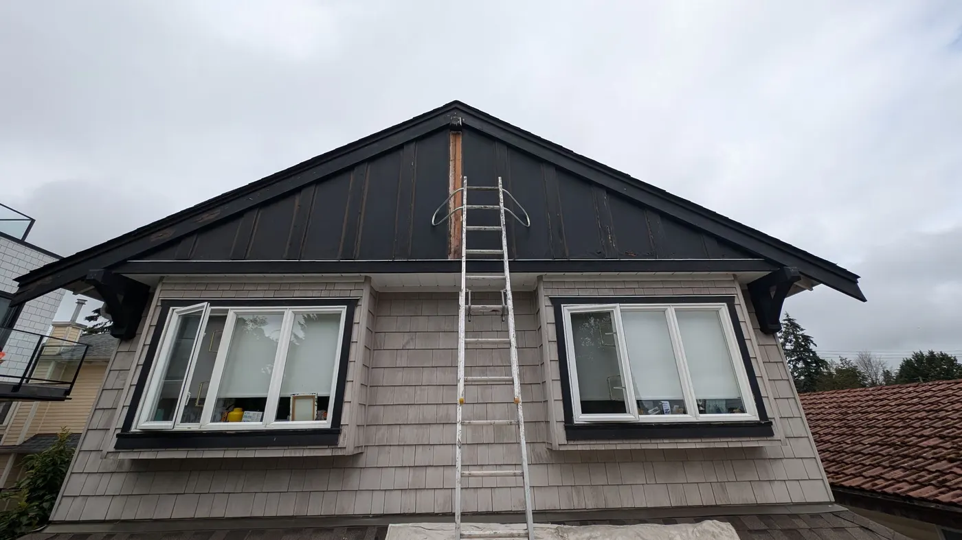 Ladder against an unpainted dark stained roof eave during exterior carpentry prep in Vancouver, BC