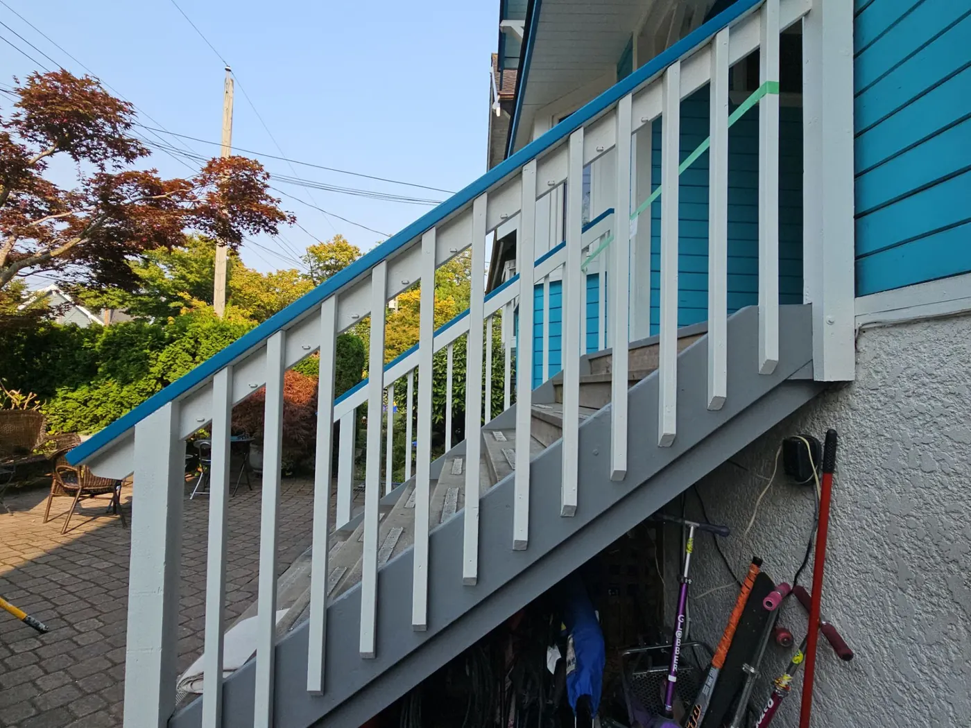 Newly painted exterior staircase with white and grey railing leading up to a turquoise Vancouver, BC home.