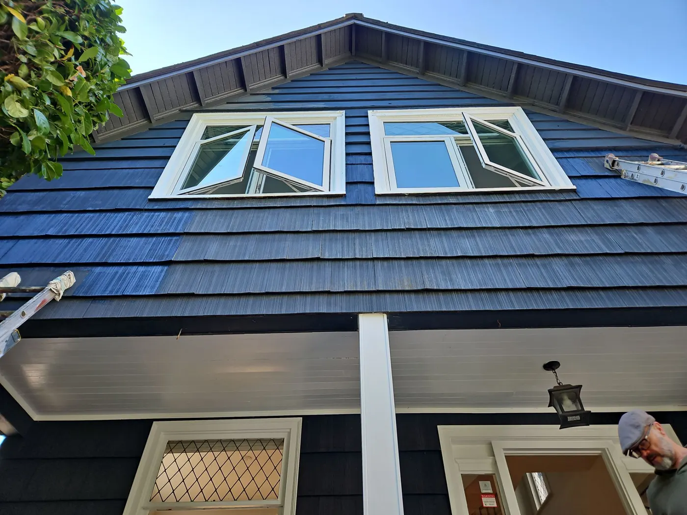 Before and after contrast on navy shingle siding around dormer windows of a Vancouver home.