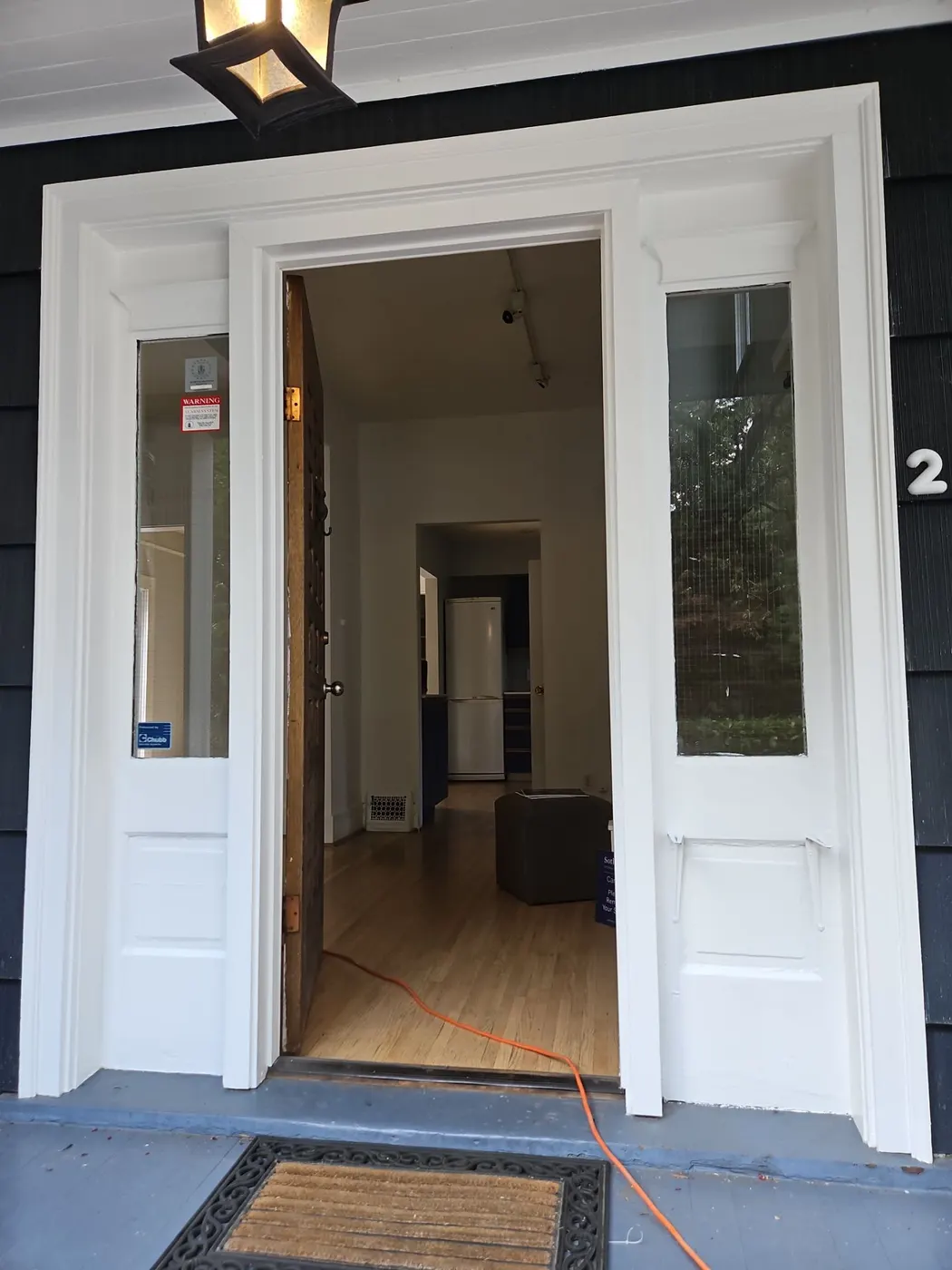 Close-up of a repainted wood front door with white trim and porch light on a Vancouver, BC home.