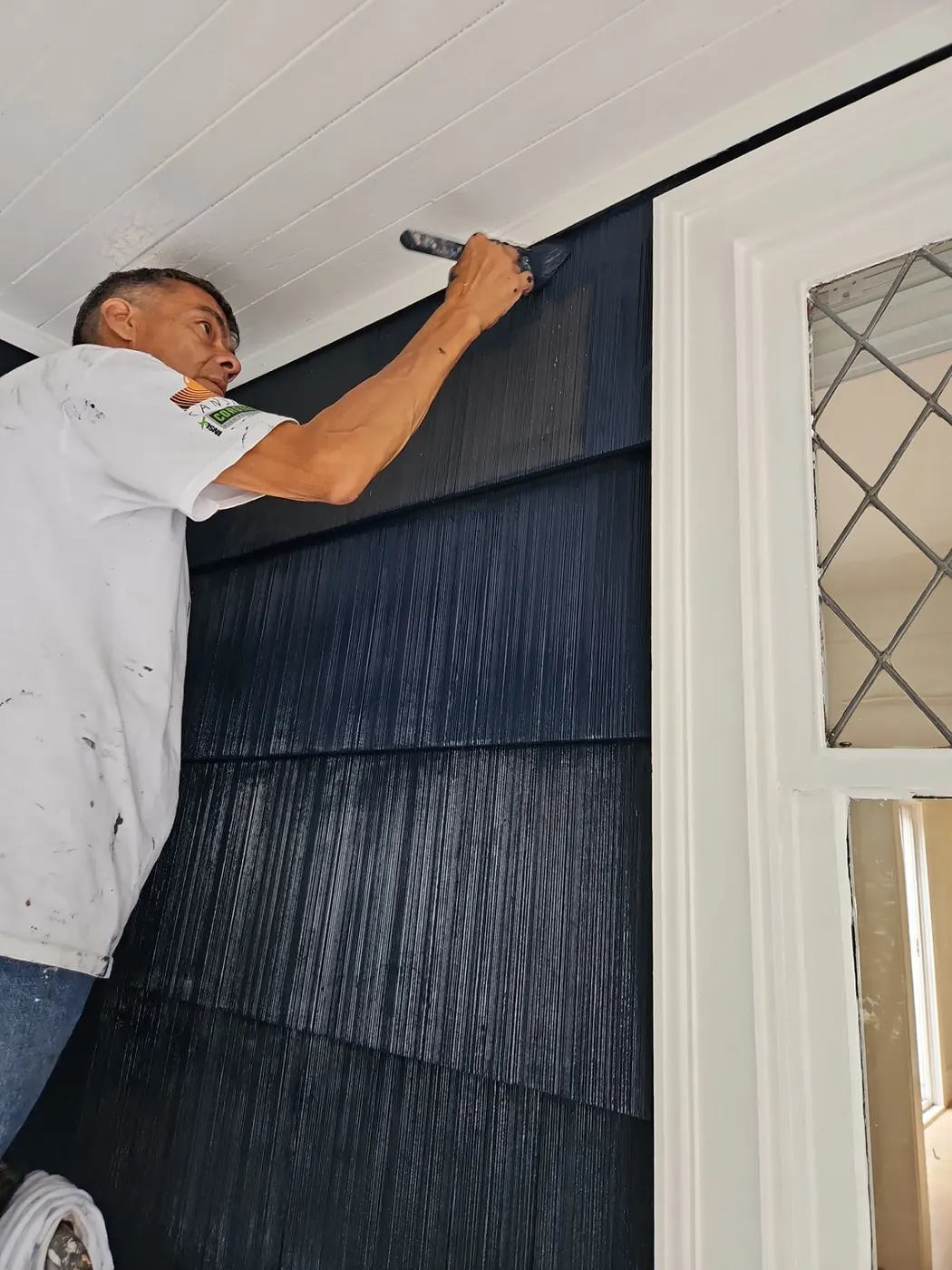 Renaissance Painting crew member brushing navy paint onto shingle siding trim in Vancouver, BC.