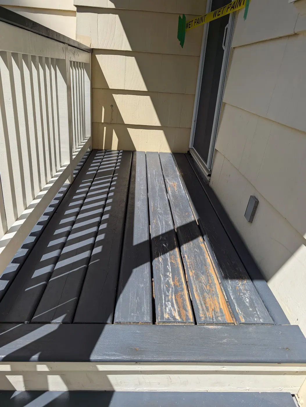Freshly painted wood deck boards with wet paint caution tape on a Vancouver home's back entry.