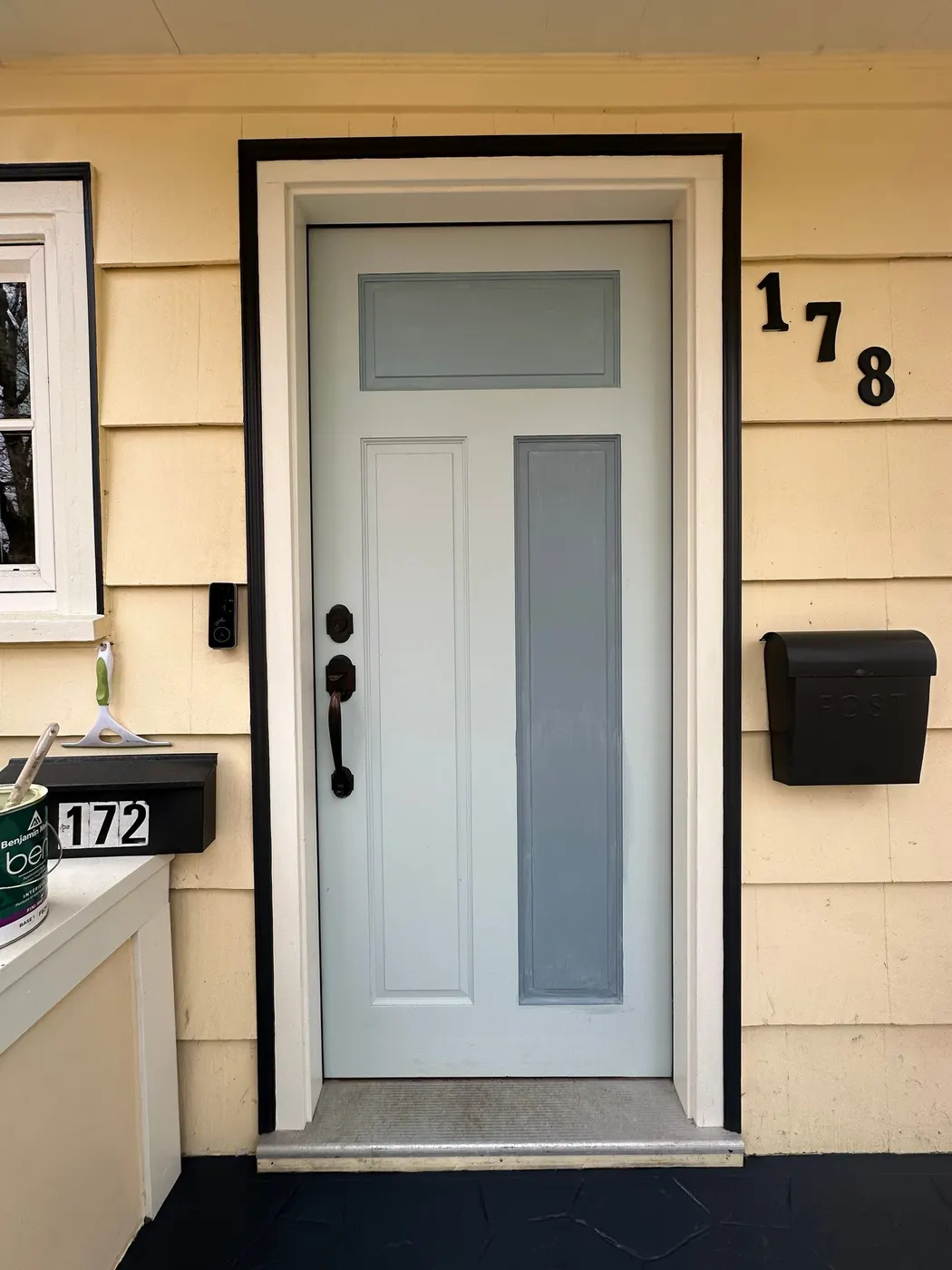 Finished soft blue-grey front door with black trim and house numbers on a Vancouver, BC craftsman home.