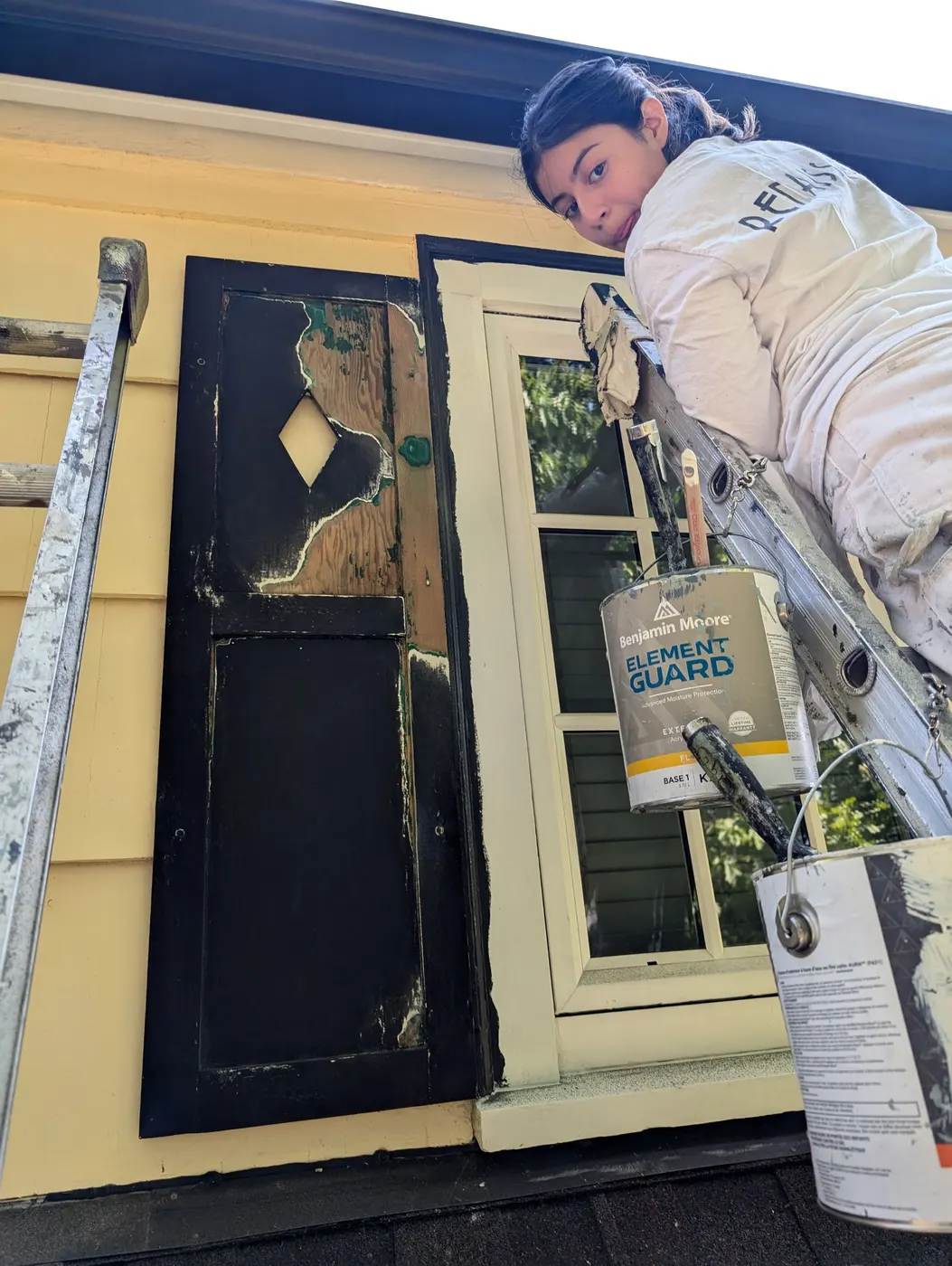 Renaissance Painting crew member repairing and repainting a wood dormer shutter on a Vancouver home exterior.