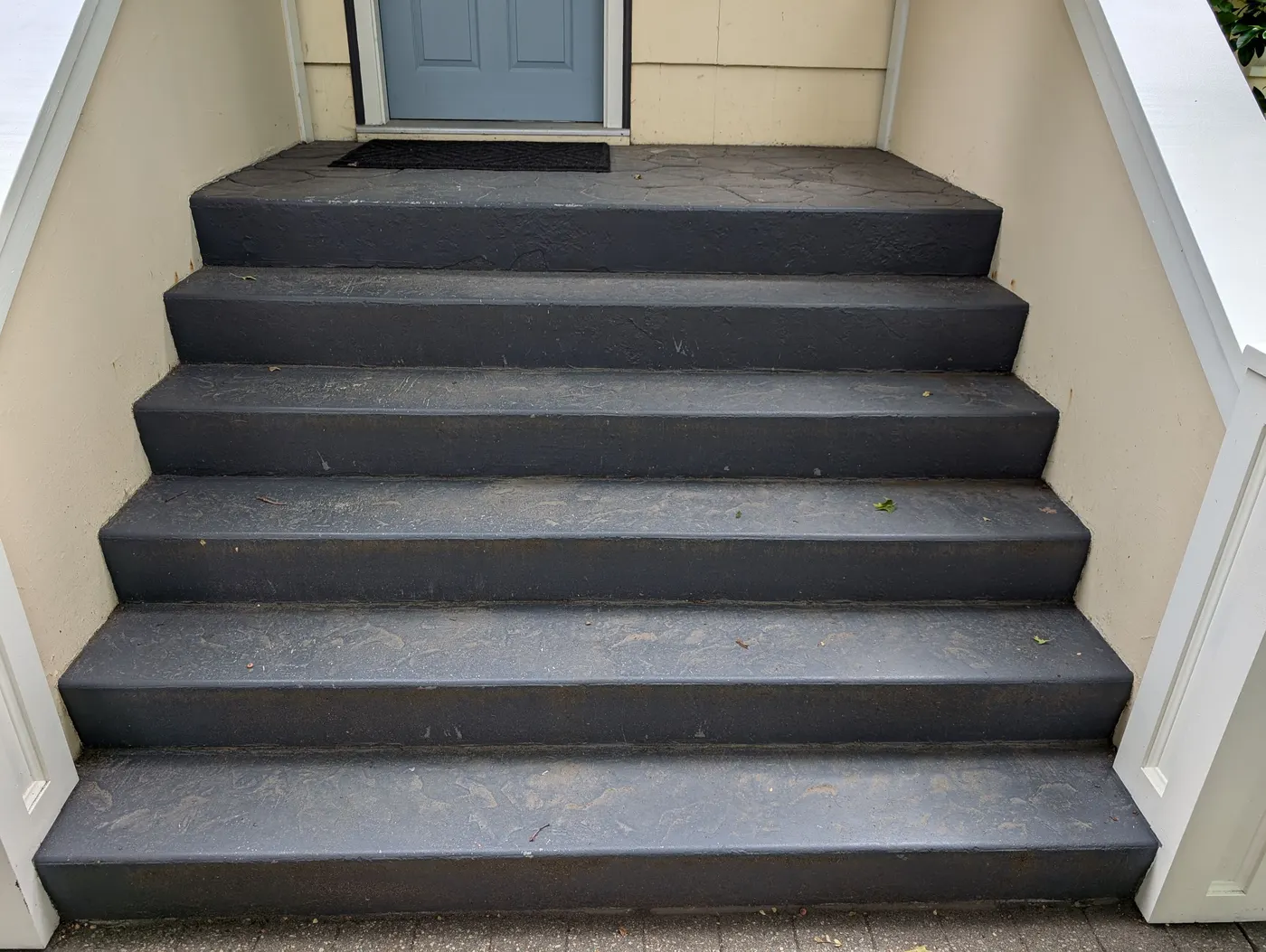 Freshly painted dark grey concrete front steps leading to a Vancouver home's entry door.